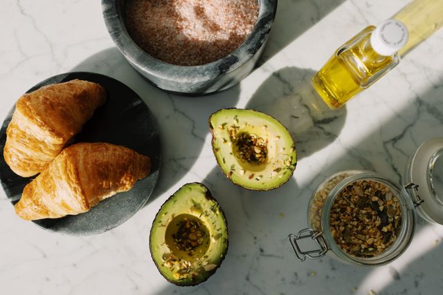 Can dogs have avocado oil: bottle of avocado oil next to fresh avocados on a kitchen table